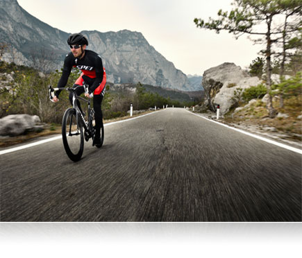 D500 photo of a mountain biker riding on a road with a mountain in the background