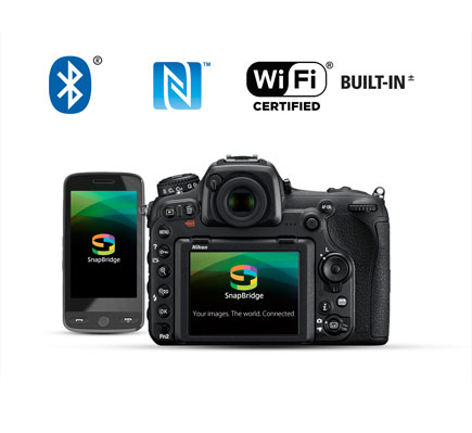 Photo of the rear of the D500 and a smartphone with the SnapBridge app logo on the LCD of both, along with the Wi-Fi, NFC and Bluetooth logos