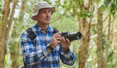 Photo of a man, with the COOLPIX P1000 in his hands, with trees in the background