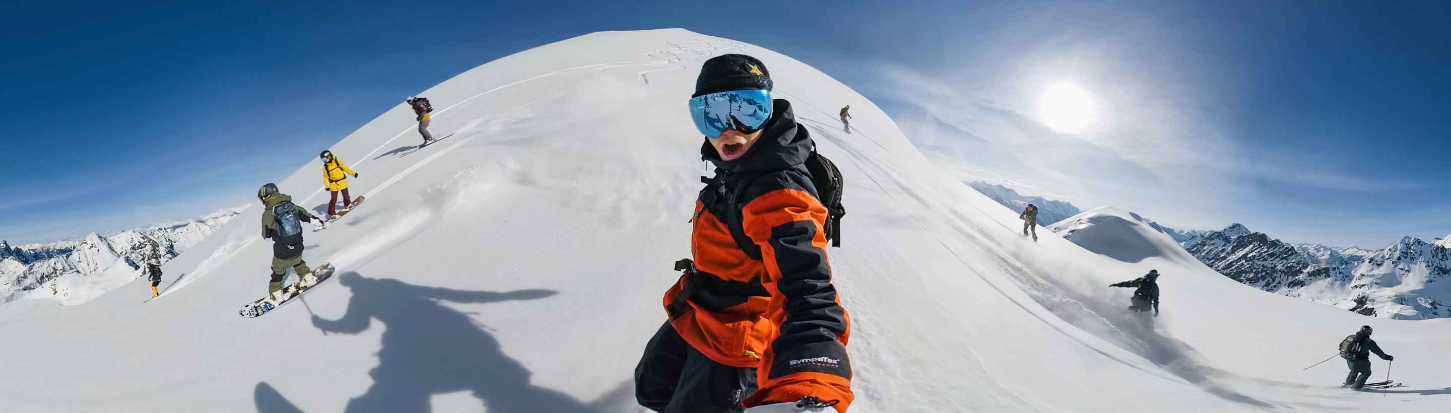Snowboarder taking a selfie with a full panoramic view of the background through the PowerPano feature.